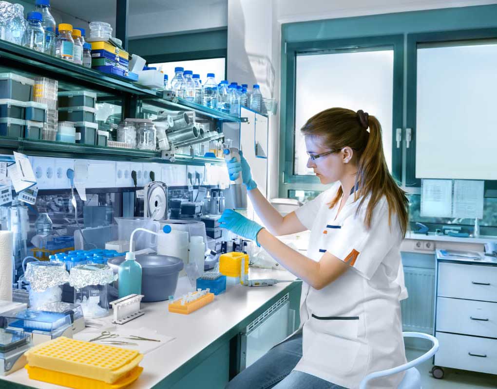 A girl wearing white lab coat testing in an laboratory